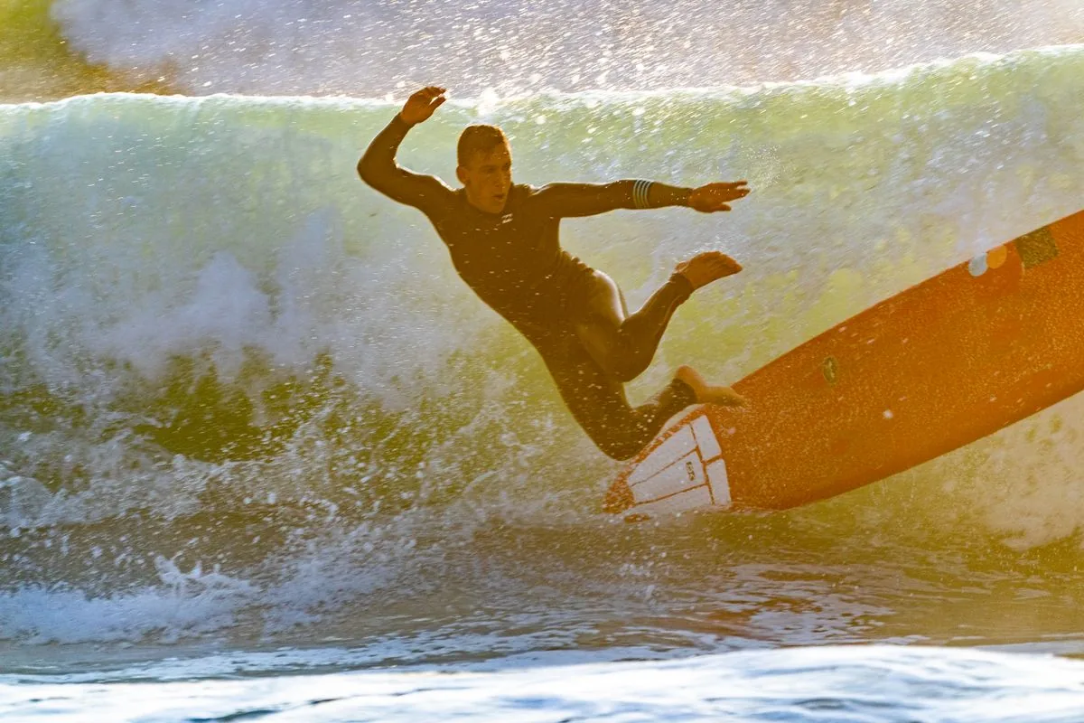 A surfer seen from behind, looking out at turquoise water