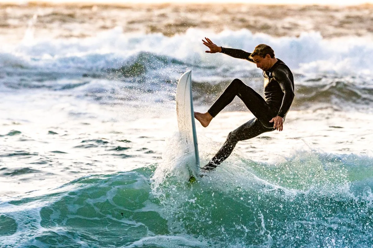 A happy surfer walking out of the water with a yellow board