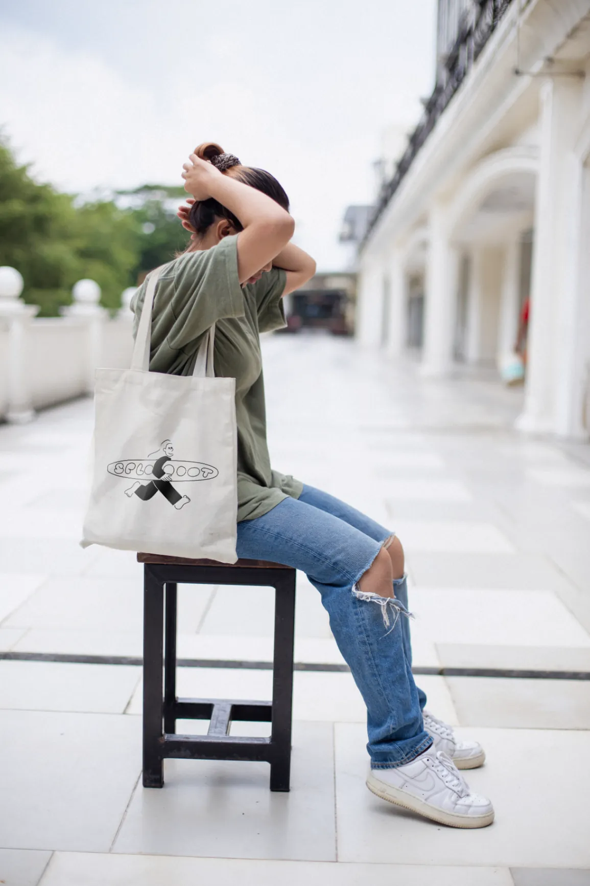 A Sploot tote bag over the shoulder of someone sitting down