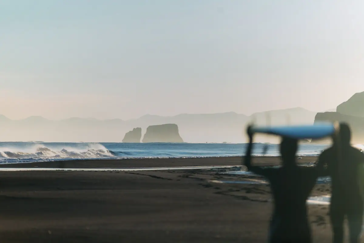 A surfboard resting on the sand with the sea and horizon behind it